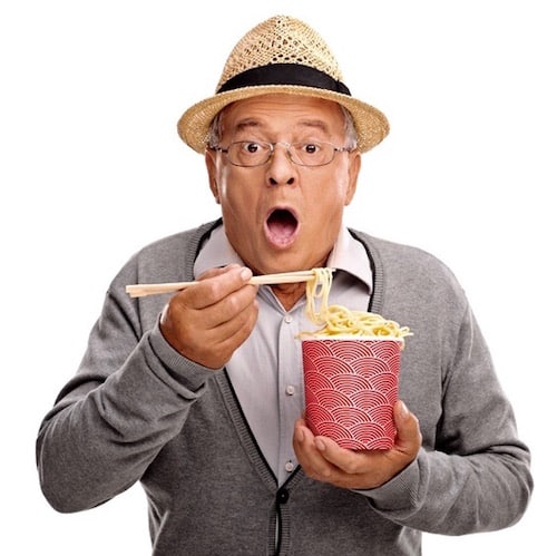 Baffled senior eating Chinese food with sticks